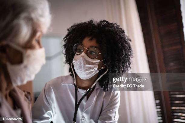 doctor using stethoscope on a senior patient at home - volunteer home care stock pictures, royalty-free photos & images