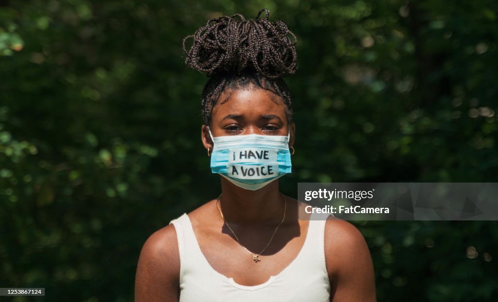 Frau trägt Gesichtsmaske mit Protestbotschaft