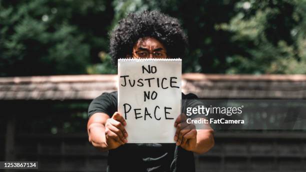 man holds up protest sign - anti racism stock pictures, royalty-free photos & images