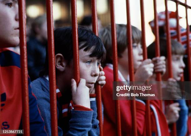 Young Manchester United fan peers through the metal railings, installed to stop pitch invasions and other crowd troubles, at Old Trafford in...