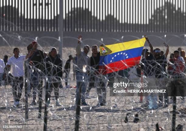 Migrants holding a Venezuelan flag wait to be processed by the Border Patrol of El Paso Sector, Texas, after crossing from Ciudad Juarez, Mexico on...