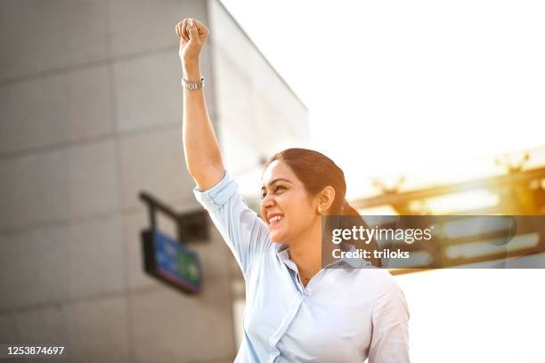 businesswoman celebrating success outside office building - fist raised stock pictures, royalty-free photos & images