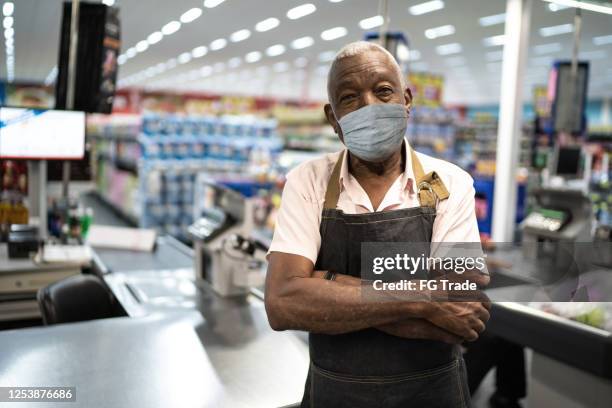 afro hogere mens bedrijfseigenaar/werknemer met gezichtsmasker bij supermarkt - vitale beroepen stockfoto's en -beelden