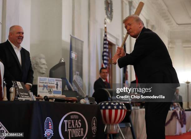 President Donald Trump holds a baseball bat while looking at exhibits during a Spirit of America Showcase in the Entrance Hall of the White House...