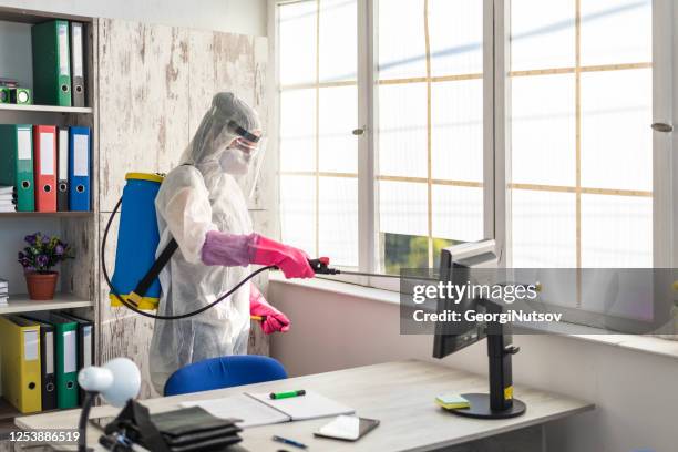 un ufficiale sanitario pulisce e disinfetta un ufficio dal covid 19 - diserbante foto e immagini stock