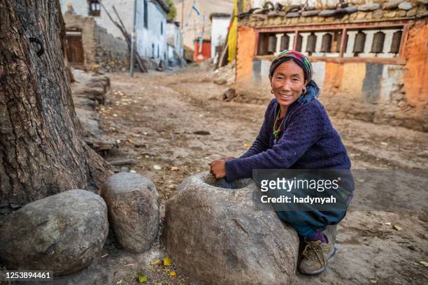 tibetan woman using a stone mortar to make flour, upper mustang, nepal - tibetan culture stock pictures, royalty-free photos & images
