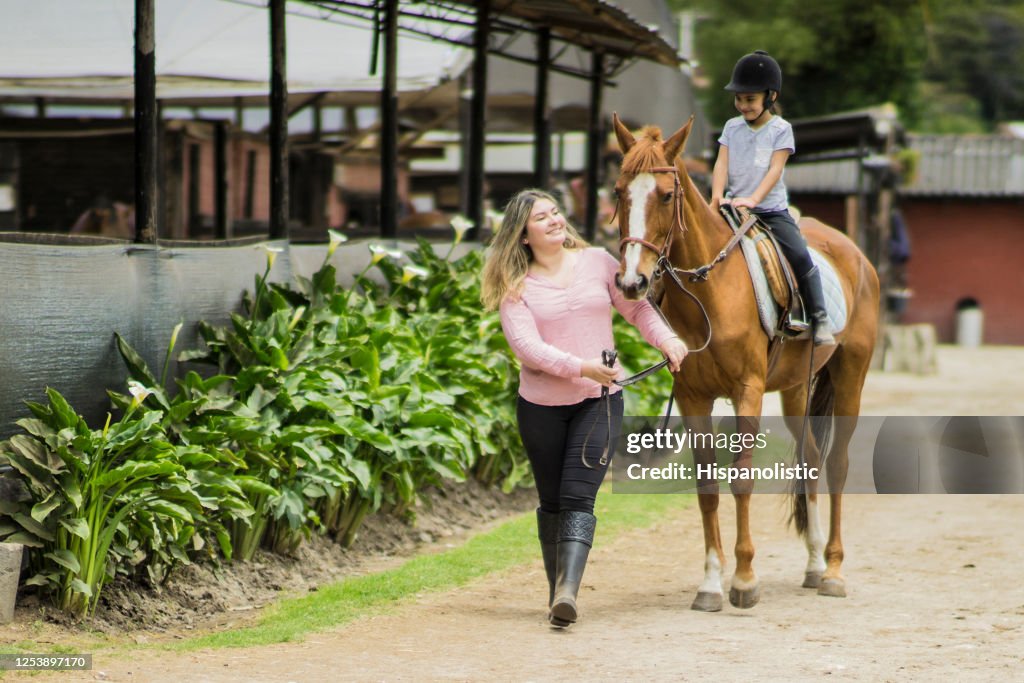Young mother teaching her daughter horseback riding