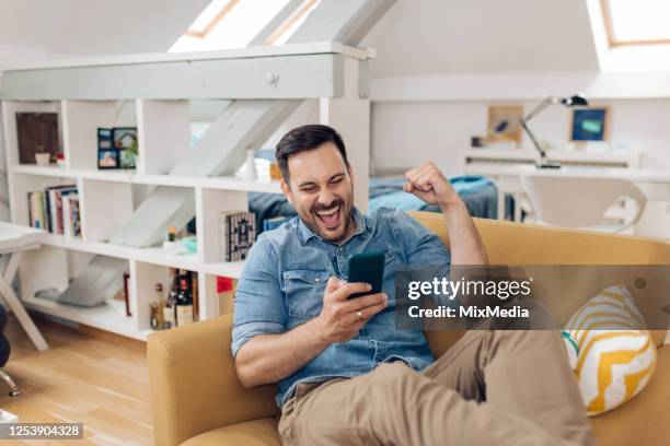 excited man watching something on the smartphone and cheering - excitement stock pictures, royalty-free photos & images