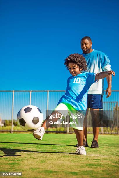 le père et le jeune fils noirs s’entraînent sur le terrain de football - father son challenge round two photos et images de collection
