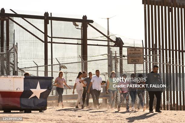 Migrants board vans after waiting along the border wall to surrender to US Customs and Border Protection Border Patrol agents for immigration and...