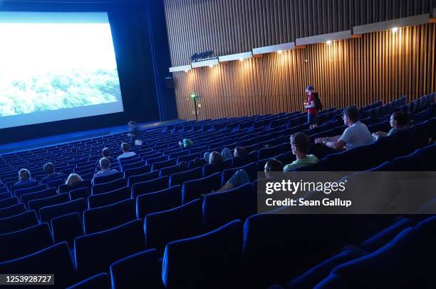 People arrive to watch a late night film at Kino International on the first day that cinemas reopened in Berlin during the novel coronavirus pandemic...