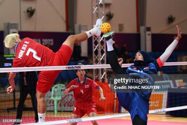 Thailand's Manlika Bunthod vies for the ball with Malaysia's Nur Athirah Roslan during their women's sepaktakraw doubles match at the 32nd Southeast...