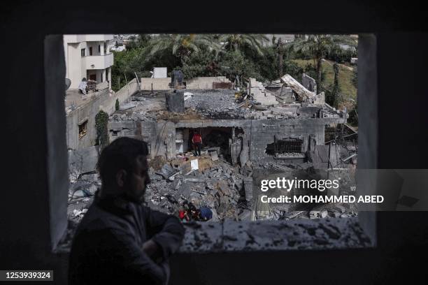 Man watches from a window as people sift through the rubble of a building hit in an Israeli air strike in Biet Hanoun, in the northern Gaza Strip, on...