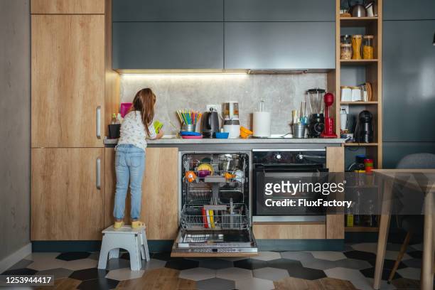 rear view of a little responsible girl washing dishes - plastic plate stock pictures, royalty-free photos & images