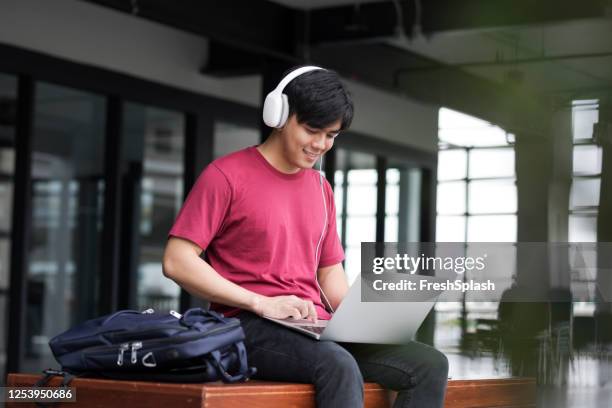 aprendizado remoto: estudante universitário sorridente ouvindo um curso online em seu laptop - korean teen - fotografias e filmes do acervo