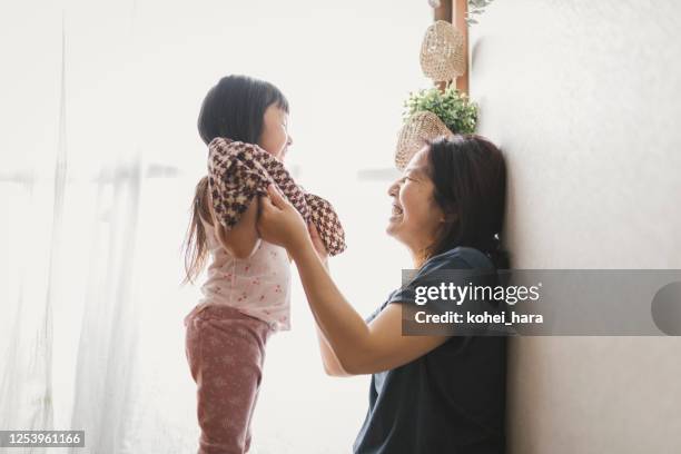 mutter hilft ihrer tochter, kleidung zu wechseln - no ordinary love stock-fotos und bilder