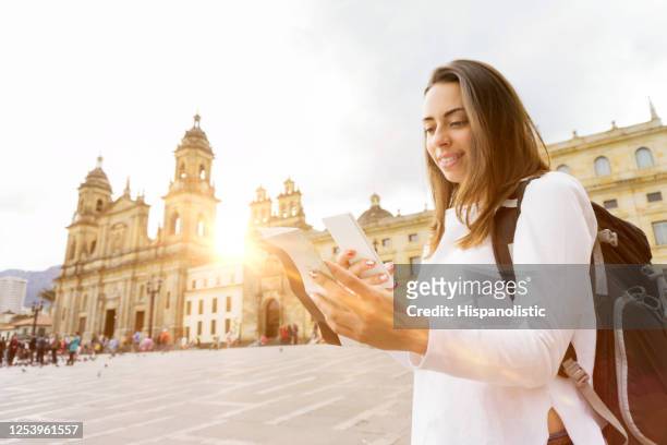 young backpacker looking at a brochure and smartphone while visiting downtown - bogota stock pictures, royalty-free photos & images