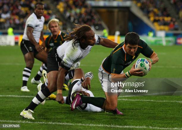 Morne Steyn of the Springboks dives past Gaby Lovobalavu of Fiji to score his team's fourth try during the IRB 2011 Rugby World Cup Pool D match...