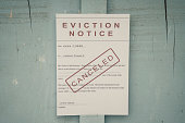 Canceled Foreclosed or eviciton notice on a main door with blurred details of a house with vintage filter.
