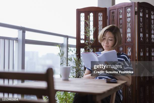 woman read analog book on the terrace room oft her house - book sleeve stock pictures, royalty-free photos & images