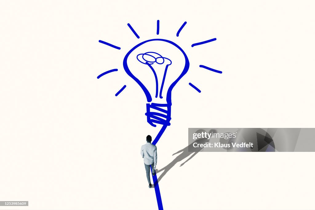 Young man walking towards bright blue bulb