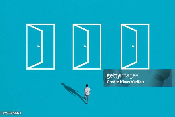 young man walking towards white doorways - pick foto e immagini stock