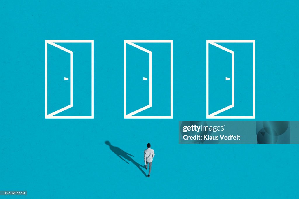 Young man walking towards white doorways