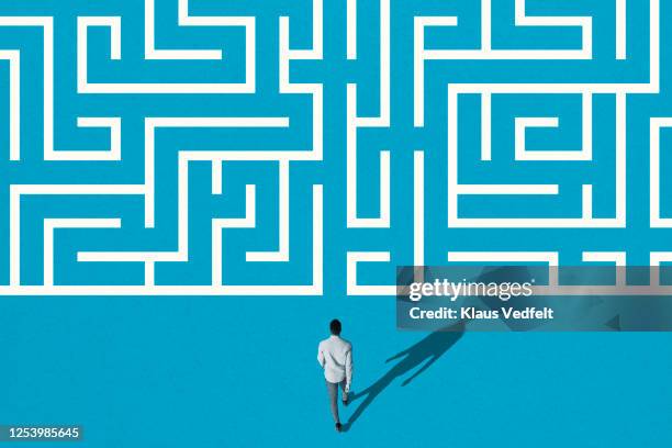 young man walking towards white maze pattern - challenge photos et images de collection
