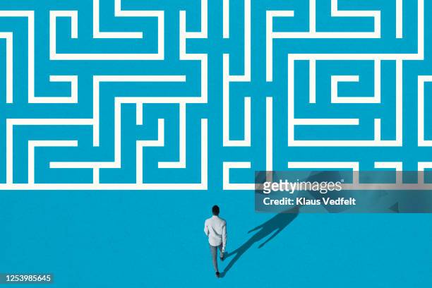 young man walking towards white maze pattern - ingewikkeldheid stockfoto's en -beelden