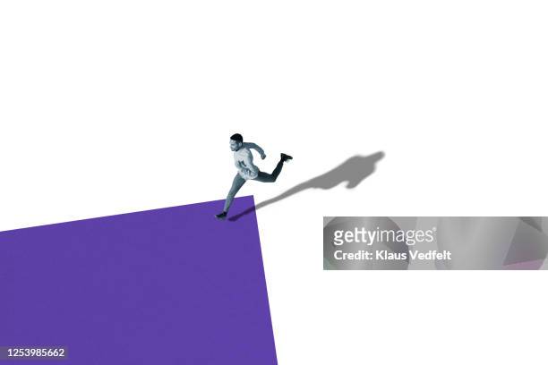 side view of young man running over purple shape - leap forward stock pictures, royalty-free photos & images