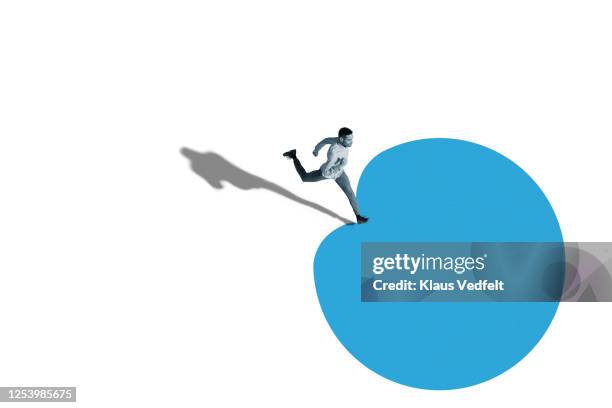 young man running over blue blob shape - elevated view of person on white background stock pictures, royalty-free photos & images