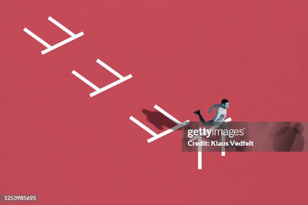 young man running in hurdle race - success story stock pictures, royalty-free photos & images