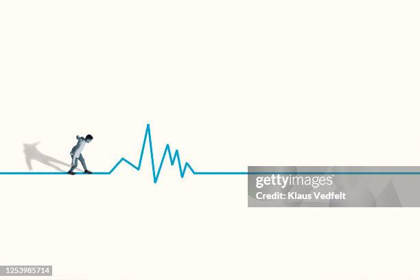 young man walking stealthily on blue line graph - line graph fotografías e imágenes de stock