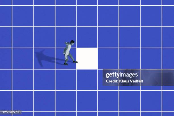 side view of young man walking on blue grid - romper el hielo fotografías e imágenes de stock