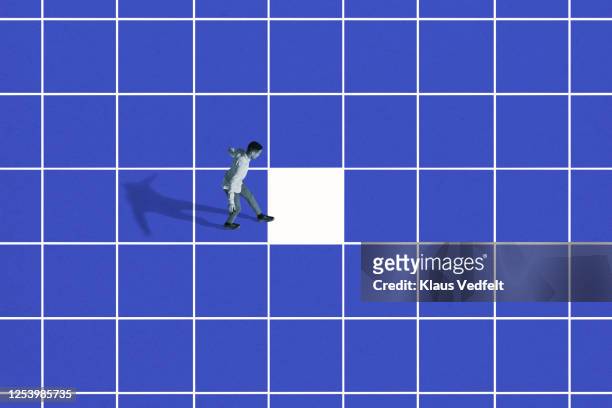 side view of young man walking on blue grid - quadrato composizione foto e immagini stock