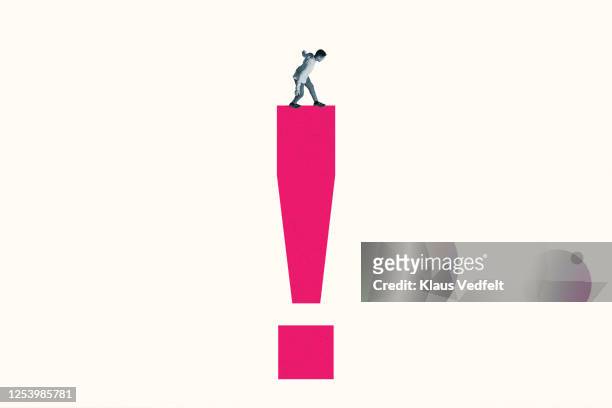 young man standing on pink exclamation point - sinal de pontuação imagens e fotografias de stock