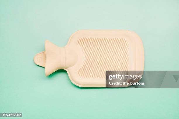 hot water bottle on turquoise background - wärmflasche stock-fotos und bilder