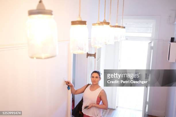 een zwangere pilatesinstructeur die de lichten bij haar studio inschakelt. - turning on or off stockfoto's en -beelden