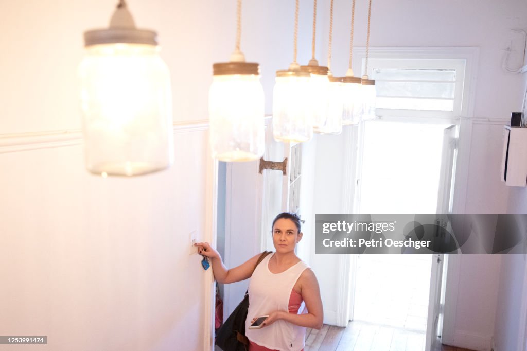 A pregnant pilates instructor turning on the lights at her studio.