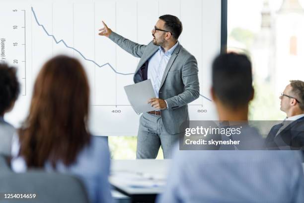 mannelijke ceo die over economische crisis op presentatie in het bureau spreekt. - economy stockfoto's en -beelden