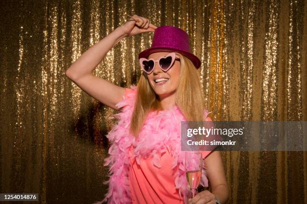 portret van medio volwassen vrouw die zich tegen gouden gekleurde achtergrond bevindt - boa persoonlijk accessoire stockfoto's en -beelden