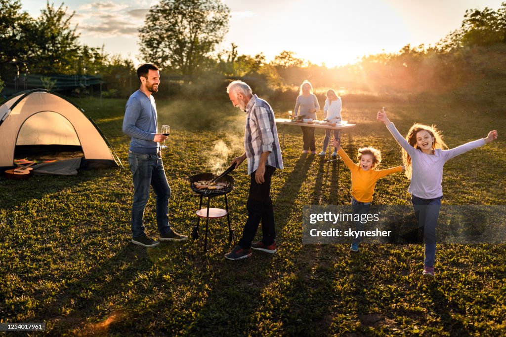 Glückliche Großfamilie mit einer Grillgartenparty bei Sonnenuntergang.