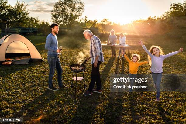 glückliche großfamilie mit einer grillgartenparty bei sonnenuntergang. - camping kid summer stock-fotos und bilder