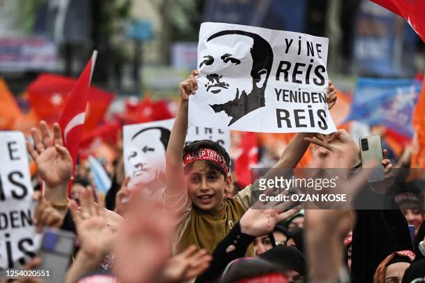 Child next to supporters of Turkish President and Leader of the Justice and Development Party, Recep Tayyip Erdogan holds a placard with the...