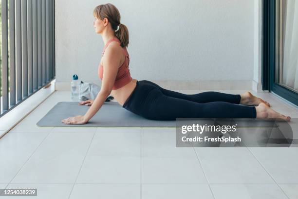 active lifestyle: a fit woman in sportswear doing yoga at home - cobra stretch stock pictures, royalty-free photos & images