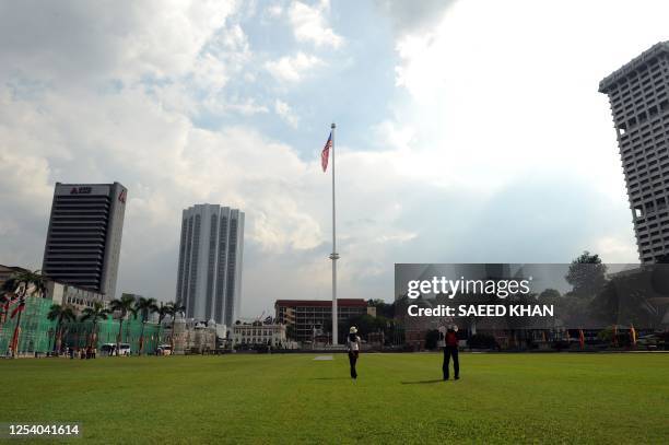 Tourists walk on the green grass of the Dataran Merdeka "Independence square" in Kuala Lumpur on February 6, 2010. A 100 metre-high flagpole rising...