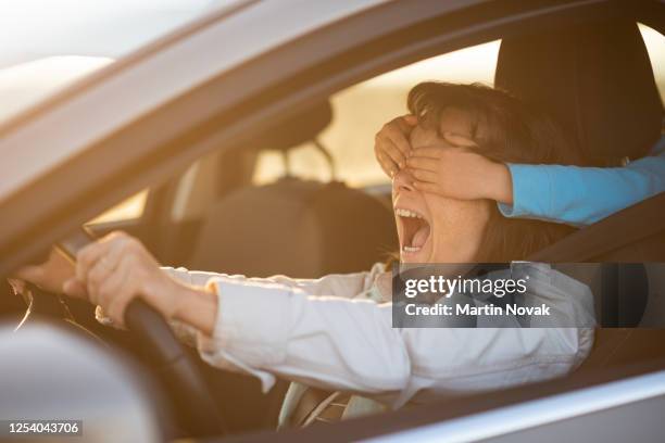 child covering eyes of her mother while driving car - blinddoek stockfoto's en -beelden