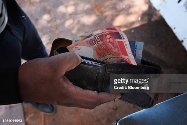 Customer with South African rand banknotes at a street vendor's stall in the Sandton district of Johannesburg, South Africa, on Friday, May 12, 2023....