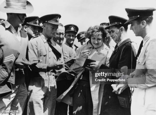 Russian discus thrower Nina Ponomaryova signing autographs for members of the Royal Australian Air Force, who surround Ponomaryova in the Olympic...