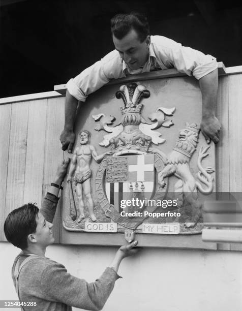 Workman affix the Coat of Arms of the Duke of Edinburgh to the Royal Box at Melbourne Cricket Ground in Melbourne, Australia, 17th November 1956. The...